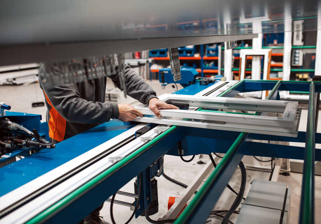 Alüminyum imalat fabrikasında çalışan, üretim hattında pencere çerçevesi monte ediyor.