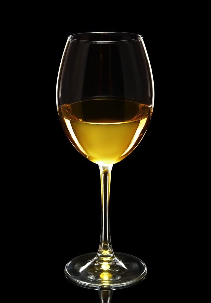 Siyah fonda beyaz şarap dolu cam kadeh ürün çekimi