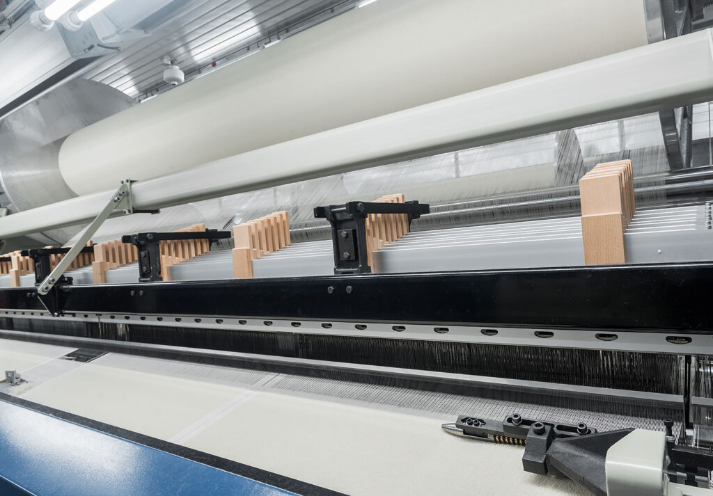 Tekstil fabrikasında dokuma tezgahı ve kumaş üretim hattı.