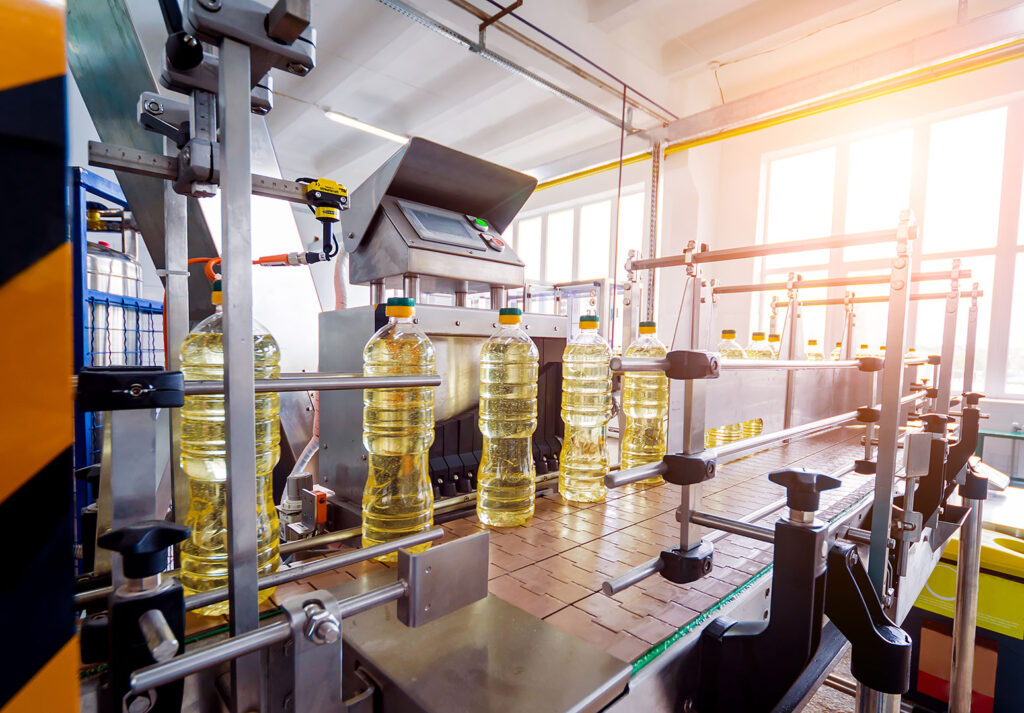 Gıda fabrikasında üretim bandında sıralanan ayçiçek yağı şişeleri.