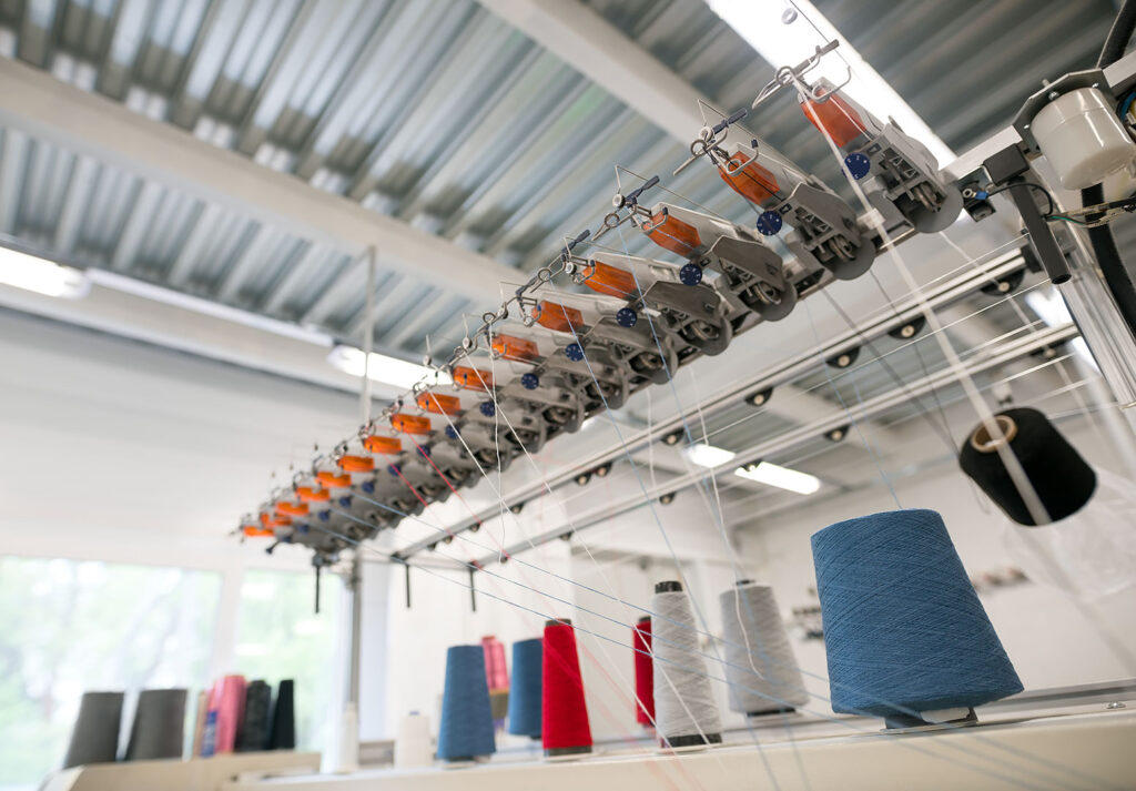 İplik üretim tesisinde iplik makineleri ve renkli bobinler.