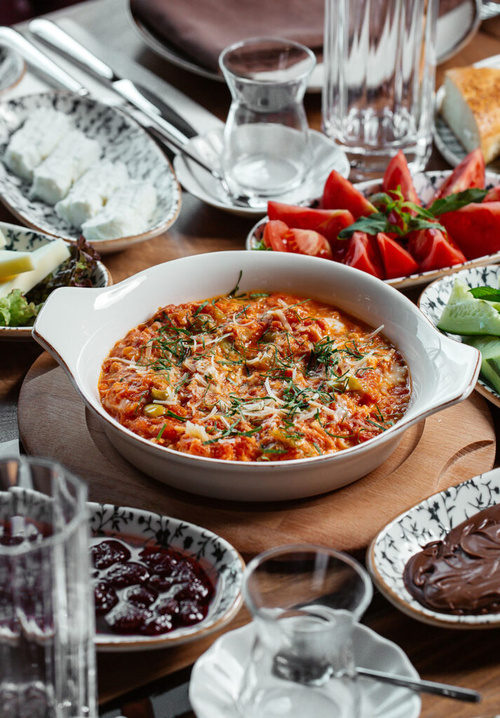 Kahvaltı masasında menemen, domates, peynir ve serpme kahvaltı çeşitleri