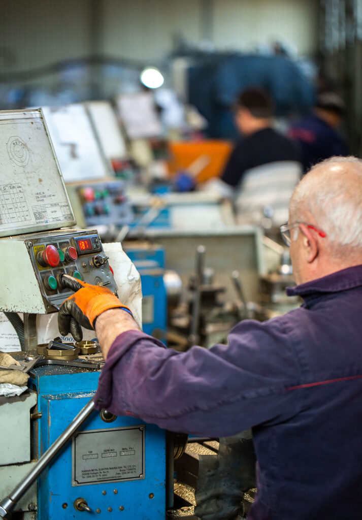 Fabrika ortamında makine operatörü kontrol paneli üzerinde çalışıyor.