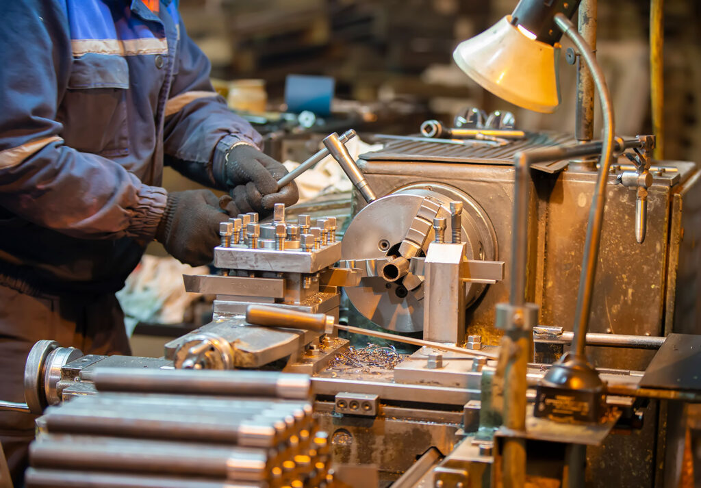 Fabrika atölyesinde bir işçi torna makinesiyle çalışıyor.