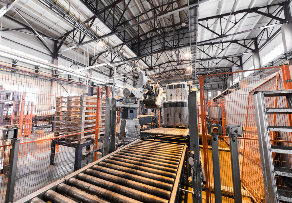 Sanayi fabrikasında üretim hattında çalışan endüstriyel robot ve konveyör bant.