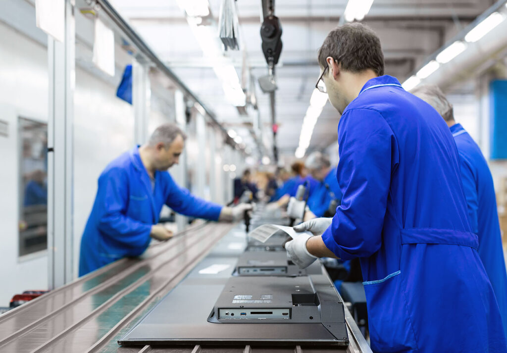 Elektronik fabrikasında çalışan işçiler televizyon üretim bandında montaj yapıyor.