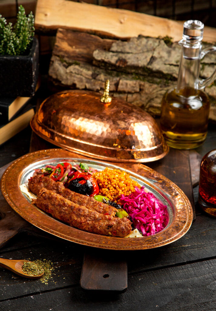 Bakır tabakta kebap, bulgur pilavı, közlenmiş sebze ve meze çeşitleri – yemek fotoğraf çekimi