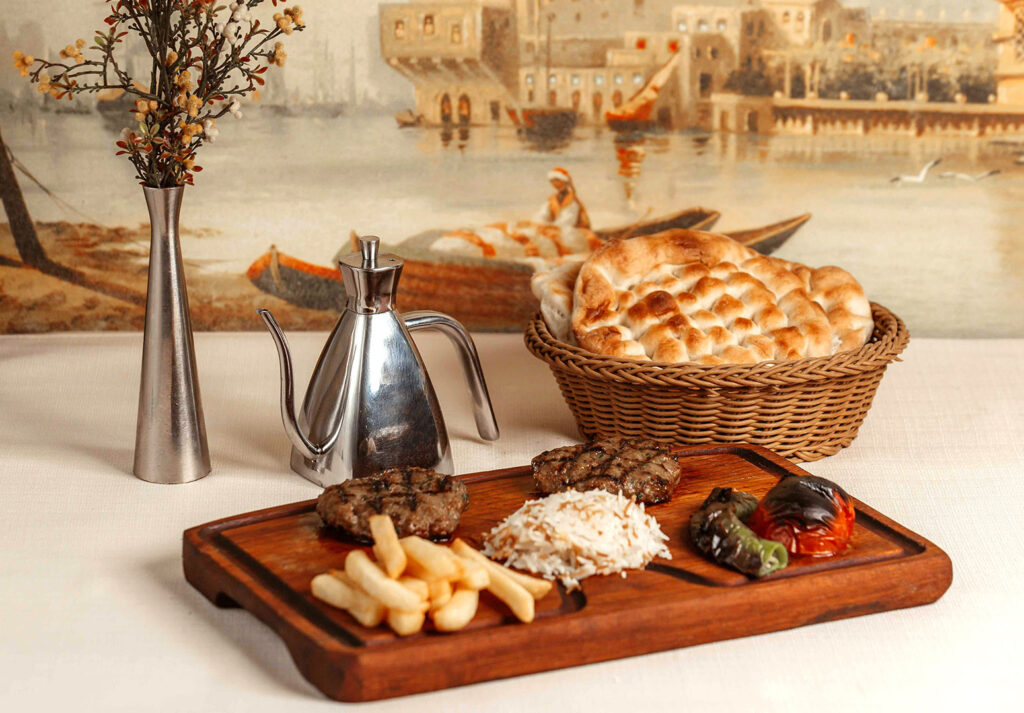 Ahşap tabakta köfte, pilav, patates ve pide sunumu – menü çekimi